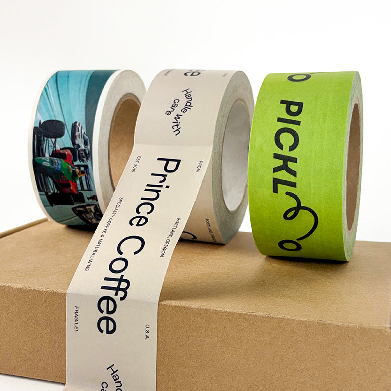 Three rolls of Self_adhesive tape with printed labels on a cardboard surface-Supr Pack